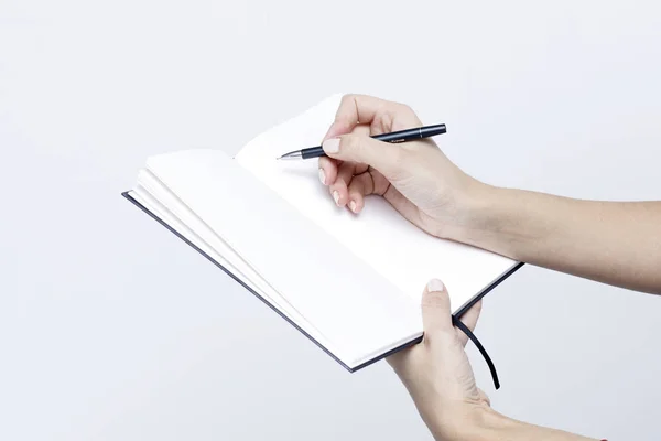 Caderno com uma caneta close-up nas mãos das mulheres em um bac branco — Fotografia de Stock