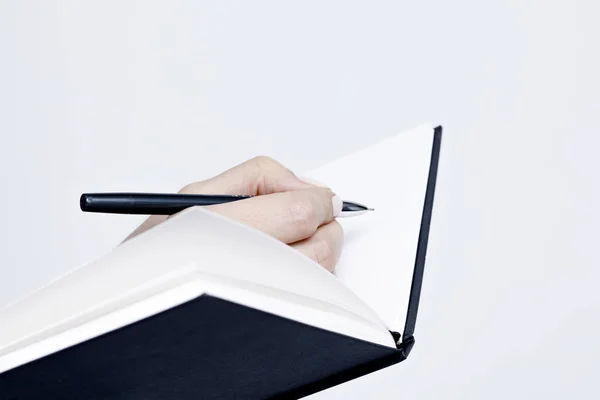 Quaderno con una penna primo piano nelle mani delle donne su un bac bianco — Foto Stock