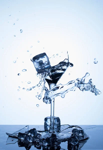 Salpicos de água. Caindo cubos de gelo em um copo de água — Fotografia de Stock