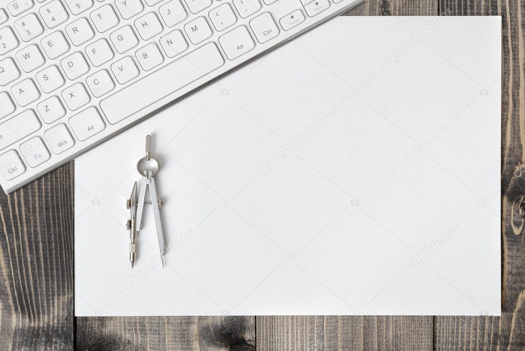 Keyboard, paper and compass on wooden plank.