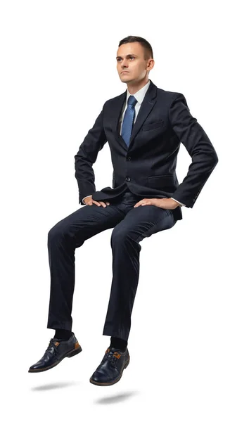 Cut-out full portrait of a businessman sitting on an invisible surface. — Stock Photo, Image