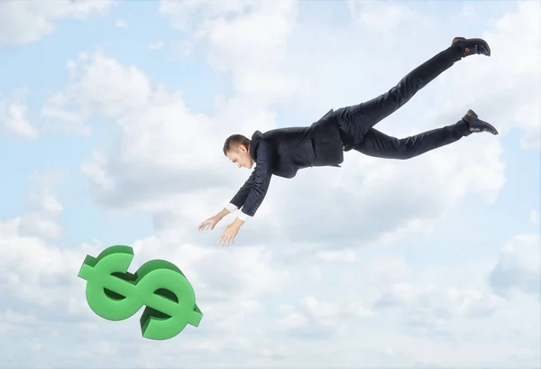 Ο επιχειρηματίας που πετούν κάτω το μεγάλο σύμβολο του δολαρίου, με outstreched τα χέρια του με φόντο το γαλάζιο του ουρανού. — Φωτογραφία Αρχείου