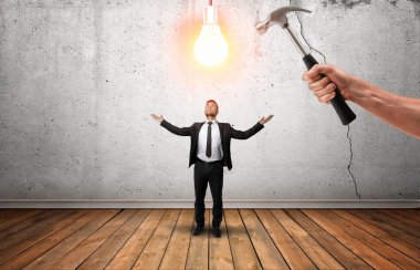 Parlayan ampul businessmans başının üzerine bir çekiç kıracağım tutan el.