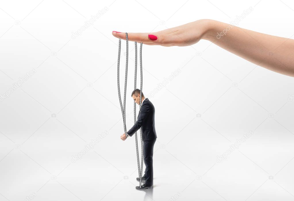 Hand pulling businessman by strings.