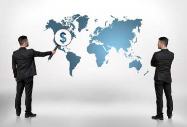 Arkadan iki işadamları büyük büyüteç büyütme Kuzey Amerika üzerinde dolar işareti ile dünya haritaya bakıyordum görünüşü.