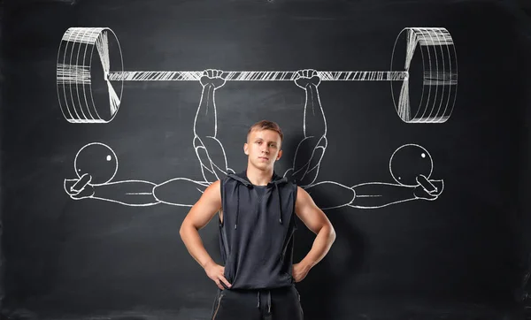 Athletic sportsman standing on the background with sketches of barbells and dumbbells. — Stock Photo, Image