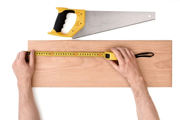 Vista de cerca de un mans manos que miden tablón de madera con línea de cinta, aislado sobre fondo blanco — Foto de Stock
