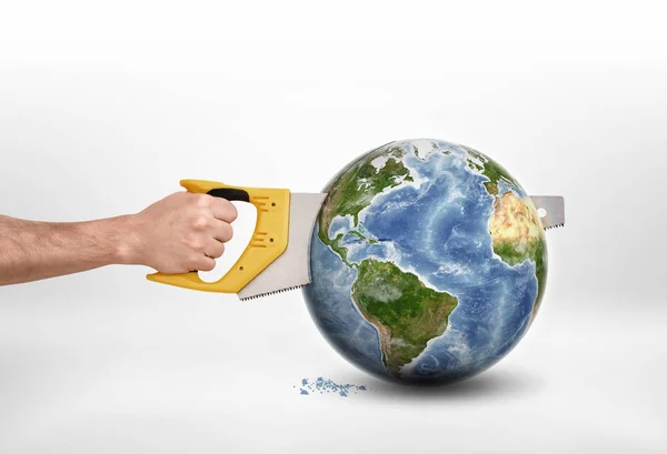 Mans hand sawing globe with saw. — Stock Photo, Image