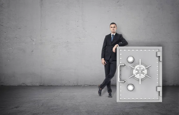 Empresario en pose de confianza de pie junto a la caja fuerte — Foto de Stock