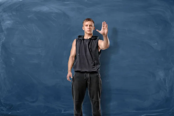 근육 질의 젊은 남자 블루 칠판 배경에 손으로 서 고 만드는 정지 신호. — 스톡 사진