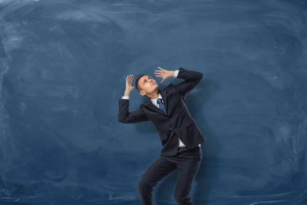 Homme d'affaires debout en pose désespérée sur fond de tableau bleu — Photo