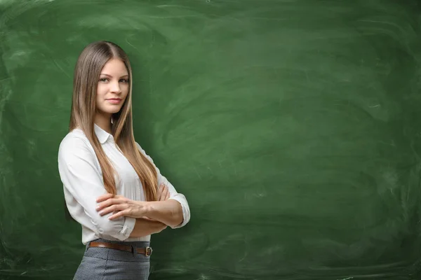 Jonge zakenvrouw met zijn armen over op groene schoolbord achtergrond — Stockfoto