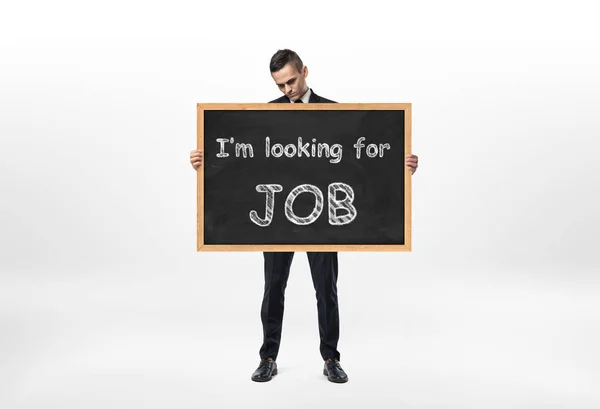 Businessman standing and holding blackboard with words Im looking for job written on it — Stock Photo, Image