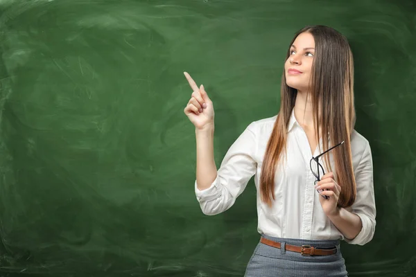 Zakenvrouw op groene schoolbord achtergrond omhoog met één vinger en op zoek in dezelfde richting — Stockfoto