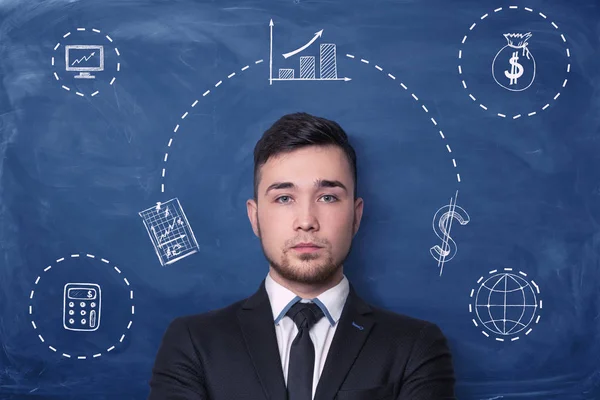 Businessman on blue blackboard background with chalk drawing of small charts, graphs, money sack and calculator. — Stock Photo, Image