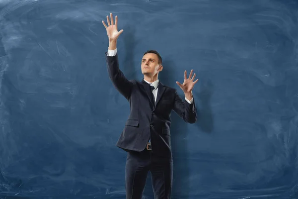 Businessman is putting imaginary buttond on the blue blackboard background — Stock Photo, Image