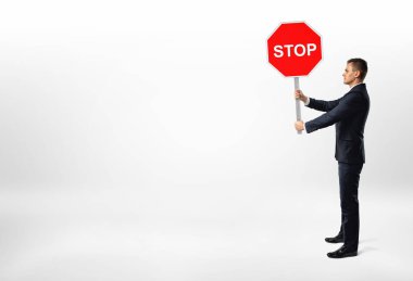 Beyaz arka plan üzerinde duran ve bir dur işareti tutan işadamı.