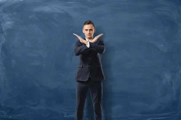 Homme d'affaires sérieux fait un stop signe avec ses mains isolées sur fond de tableau noir bleu — Photo