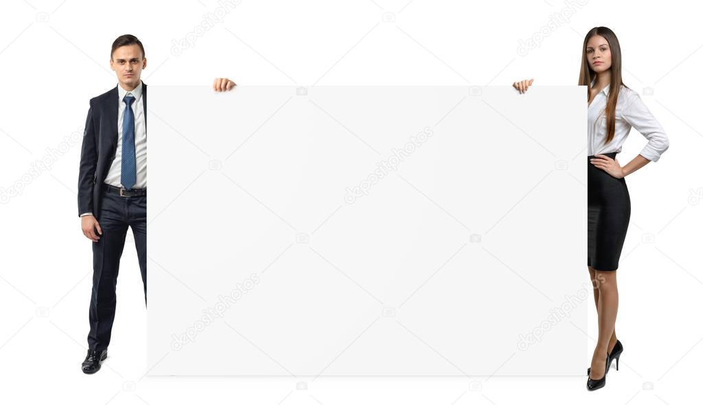 Businessman and businesswoman are holding both sides of a blank banner isolated on white background