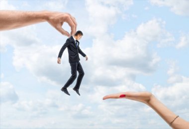 Mans el mavi gökyüzü backgroung üzerinde küçük bir işadamı bir kadının el taşıyan