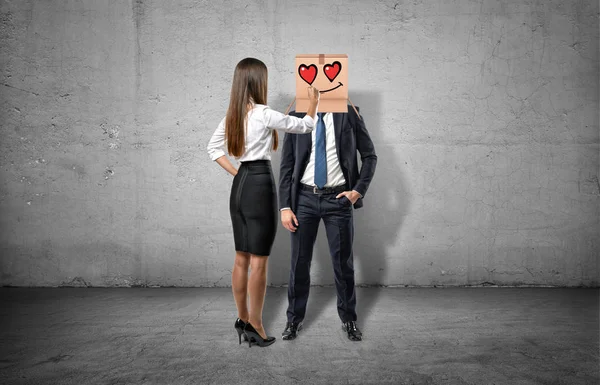 Femme d'affaires dessine un visage amoureux sur la boîte qui cache un visage d'homme d'affaires — Photo