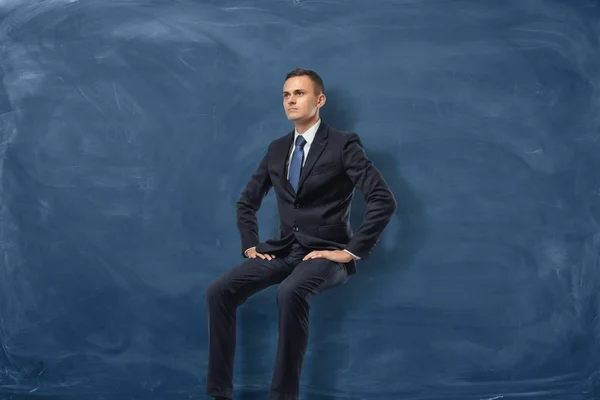 Homme d'affaires est assis et pensant isolé sur fond de tableau bleu — Photo