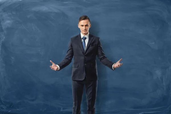 Homme d'affaires réussi est debout avec les bras ouverts isolés sur fond de tableau bleu — Photo