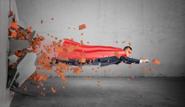 Şu moloz arkasında bırakarak duvarın üzerinden uçan pelerinli bir süper kahraman işadamı.