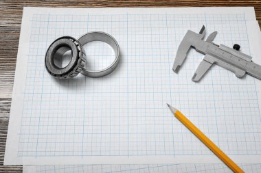 Bir yatak tutan bir vernier Kaliper, bir kalem ve kağıt üzerinde hazırlanması üzerinde yalan bir çift of pergel ahşap arka plan.