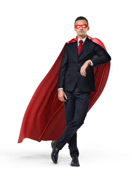 En superhjälte i kostym och en röd cape lutande på en osynlig objekt på vit bakgrund. — Stockfoto