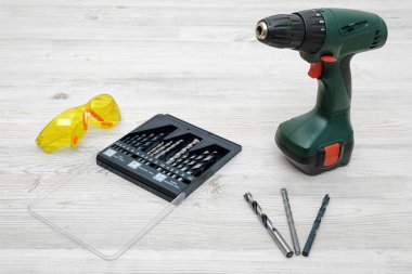 Ahşap masa arka plan bit kutu ve çevresinde sarı koruyucu gözlük bir dizi ile üzerinde durmak için ayarla Akülü matkap.