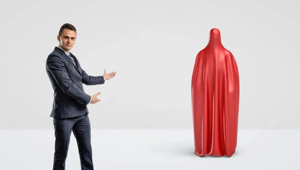 Um homem de negócios mostrando uma silhueta humana coberta com um pano vermelho atrás dele . — Fotografia de Stock