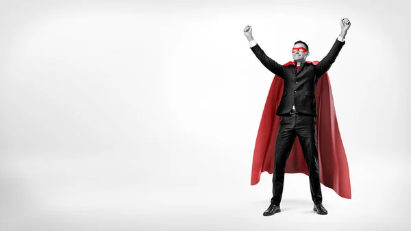 Un uomo d'affari felice in un mantello rosso supereroe in piedi in posa vittoria su sfondo bianco . — Foto Stock