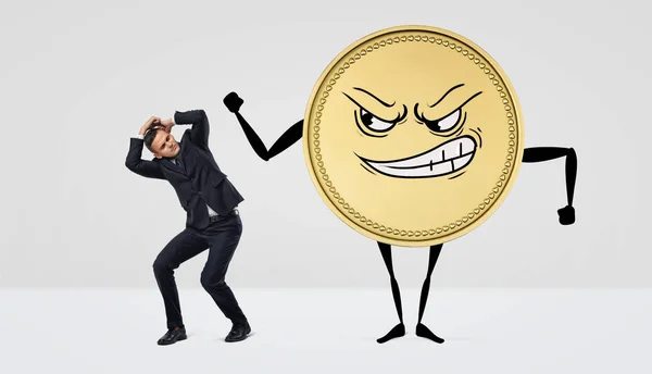 Eine riesige humanoide Münze mit wütendem Gesicht, die auf einen Kleinunternehmer einschlägt. — Stockfoto