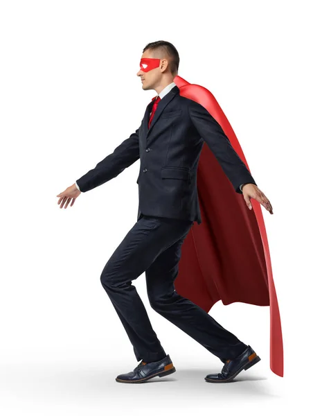 En superhjälte i kostym och en röd cape att hålla balansen på ett osynligt rep. — Stockfoto