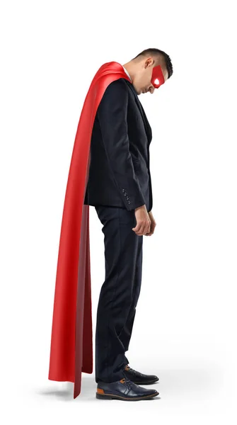 Грустный бизнесмен в красном плаще супергероя, стоящий с опущенными плечами и смотрящий вниз . — стоковое фото