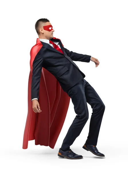 En affärsman i en röd superhjälte cape och en mask halka och falla baklänges. — Stockfoto