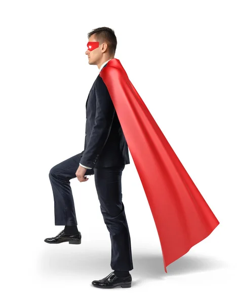 Ein Geschäftsmann in fließendem roten Umhang tritt auf eine unsichtbare Leiter. Fortschritte. — Stockfoto