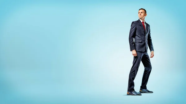 Un uomo d'affari in piedi su sfondo blu a metà turno e guardando oltre la sua spalla . — Foto Stock