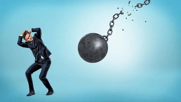 Gizlemek ve kendini yırtık bir zincir ile düşen bir yıkım topu karşılamak için küçük bir iş adamı.