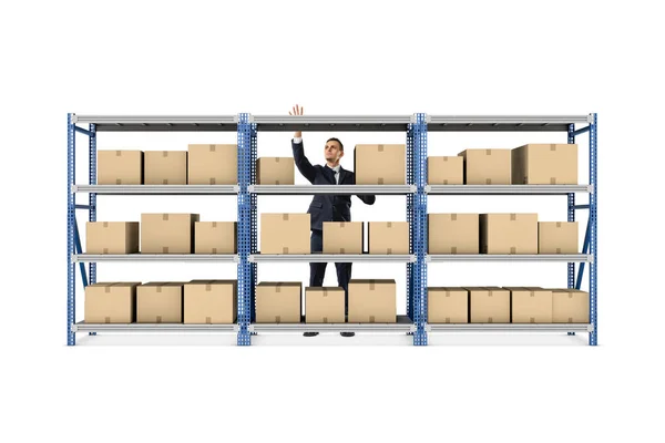 Podnikatel, stojící za kovovou skladu stojan plný krabic na bílém pozadí. — Stock fotografie