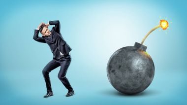 Gizleme ve kendini yaktı bir sigorta ile dev bir siyah bomba yanında kapsayan korkmuş bir işadamı.