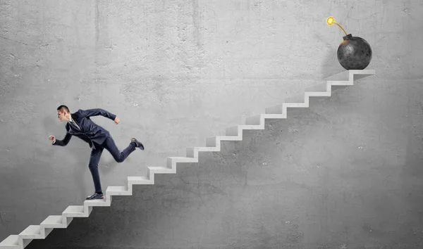 Korkmuş bir işadamı bir büyük demir bomba aydınlatılmış bir sigorta ile uzak gri beton merdiven aşağı koşma.