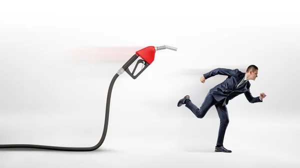 Egy üzletember, fehér alapon fut el egy piros gáz fúvóka csatlakozik egy fekete tömlő. — Stock Fotó