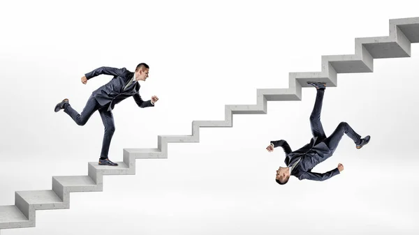 Dos hombres de negocios corriendo escaleras de hormigón en volcado imagen reflejada el uno del otro . — Foto de Stock