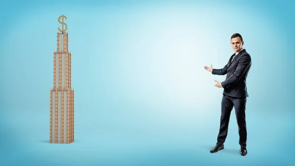 Крупный бизнесмен показывает бизнес-здание с золотой табличкой USD на вершине . — стоковое фото