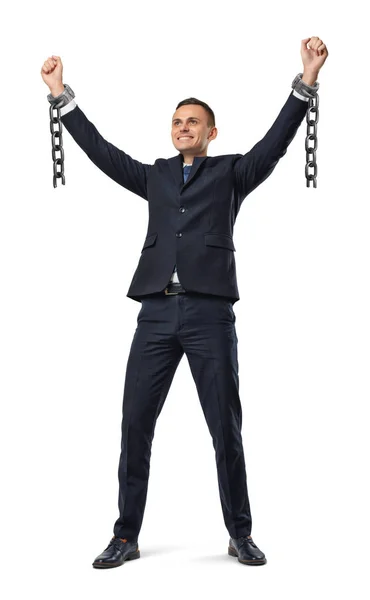 A happy businessman with hands raised up showing broken shackles on white background. — Stock Photo, Image