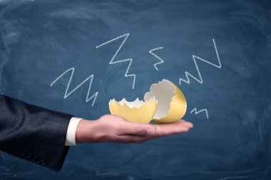 Yazı tahtası etrafında çizilmiş negatif oklarla businessmans avuç içinde yalan bir büyük kırık ve boş altın yumurta.