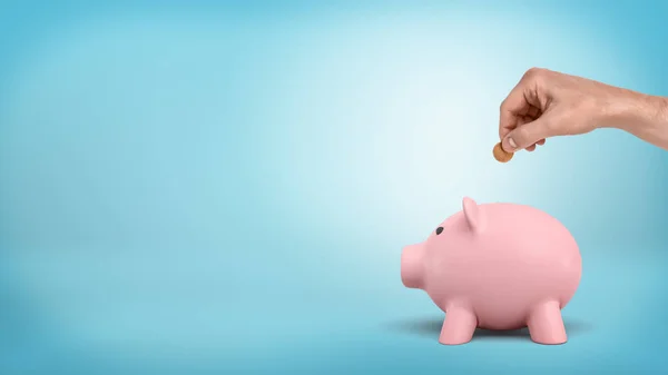 Eine männliche Hand hält eine 50-Cent-Münze über einem Schlitz auf Sparschweinen auf blauem Hintergrund. — Stockfoto
