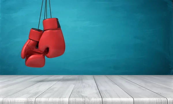 Rendu 3d de deux gants de boxe rouges suspendus au-dessus d'un bureau en bois devant un fond de tableau noir bleu . — Photo